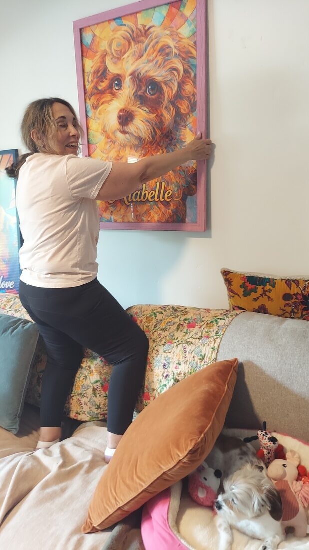 Mercy hanging a finished framed Pet Pic Portraits portrait on a wall